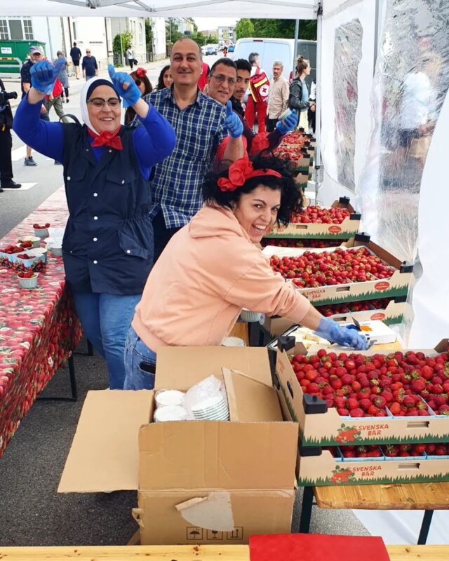 Glada personer delar ut jordgubbar