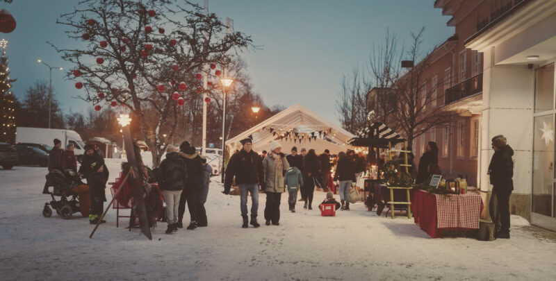 Många människor strosar på julmarknad i snöig småstad