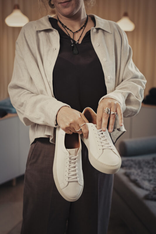 Kvinna håller i vita skor i klädbutik