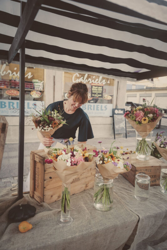 Kvinna säljer blomsterbuketter i marknadsstånd